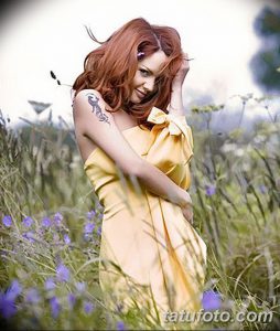 Фотография девушки в желтом платье с татуировкой на плече. Девушка смотрит в камеру, ее волосы распущены. Татуировка выполнена в стиле трайбл.