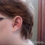Фото тату: пирсинг хряща уха с красным украшением. Необычный и яркий акцент в образе. Подходит для смелых личностей.