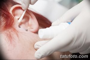 Фото процесса ухода за свежим пирсингом уха с использованием антисептика и ватной палочки. Важный этап заживления.