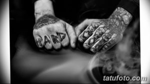 Фото рук мужчины с татуировками надписей "HARD CORE" на костяшках пальцев и сложными рисунками на тыльной стороне ладоней. Демонстрация смелого и выразительного стиля.