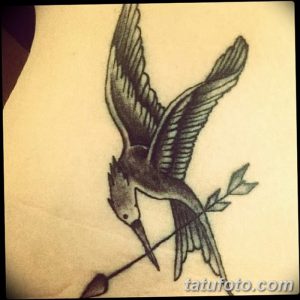 Фото тату птицы, пронзенной стрелой, выполненной в технике blackwork на руке. Детализированный рисунок татуировки с акцентом на крылья и оперение.