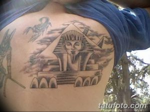 Фото тату на плече с изображением сфинкса и пирамид. Черно-серый рисунок с проработкой деталей и теней.