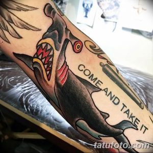 Фото татуировки акулы-молота в стиле олдскул с надписью 'Come and take it'. Яркие цвета и четкие контуры.