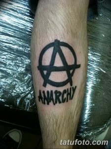 Фото тату: Черная татуировка символа анархии и надписи 'ANARCHY' на руке. Минималистичный эскиз татуировки.