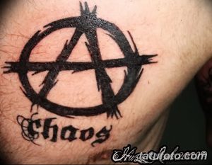 Фото тату: символ анархии и надпись 'Chaos'. Черный контур, брутальный стиль, символ протеста и разрушения.