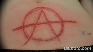 Фото тату на животе: символ анархии. Простой и минималистичный рисунок татуировки, выполненный в красном цвете.