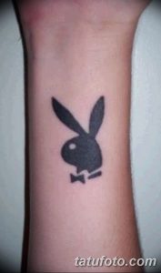 Фотография небольшой татуировки в виде логотипа Playboy (голова зайца с бабочкой) на запястье. Черно-белое изображение, выполненное в простом стиле.