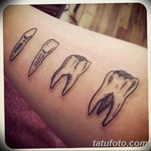 Фотография набора татуировок зубов разных форм и размеров, расположенных на руке. Рисунок татуировки выполнен в черно-белом стиле.