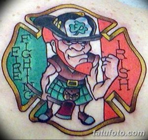 Фото тату лепрекона в ирландском стиле, окруженного надписями "Fight Irish", выполненное в ярких цветах. Рисунок расположен на коже и отличается детализацией и реалистичностью.