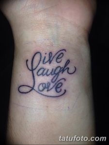 Фото тату на запястье: надпись 'Live, Laugh, Love' выполненная изящным курсивом, черным цветом.