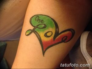 Фото тату сердца, разделенного на три секции разных цветов с надписью 'One Love' на предплечье. Цветная татуировка, выполненная в графическом стиле. Эскиз тату для позитивных людей.