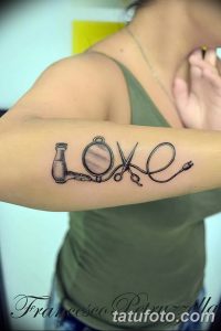 Фото тату на руке: машинка для стрижки, ножницы и провод, образующие слово 'Love'. Эскиз татуировки символизирует любовь к профессии парикмахера.