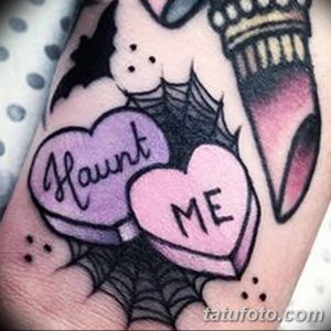 Яркая татуировка на руке в стиле конфетных сердечек с надписью "Haunt Me". Символ милой, но немного мрачной любви.