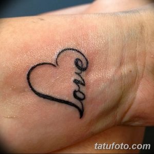 Фото тату: надпись 'Love' вписана в контур сердца на запястье. Черно-белая татуировка небольшого размера, популярный выбор для девушек.