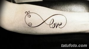 Фото тату бесконечности с надписью 'Love' на запястье. Изящный рисунок татуировки выполнен в коричневых тонах.