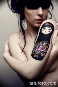 Фото тату матрешки на плече, украшенной цветами и выполненной в нежных, пастельных тонах. Романтичный эскиз тату для девушек.