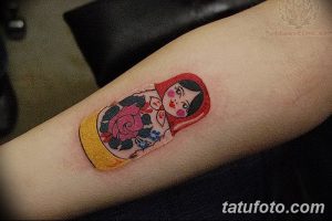 Фото тату матрешки с розами, выполненное в красных и черных тонах. Классический эскиз тату для любителей традиционного искусства.