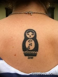 Фото минималистичной татуировки матрешки на спине. Рисунок выполнен в черном цвете и имеет простой, лаконичный дизайн. Под матрешкой указан год - 2010.