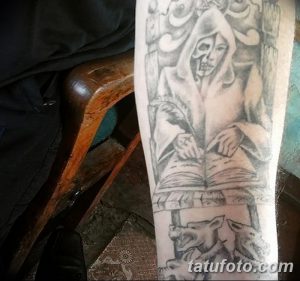 Фото тату: реалистичное изображение писца, пишущего в книге, выполненное в черно-серых тонах на руке. Детализированный рисунок.