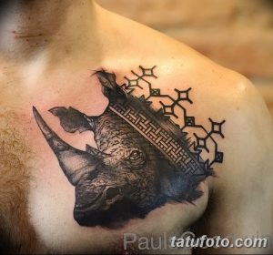 Фото татуировки носорога с геометрическим фоном на груди. Рисунок выполнен в черно-серых тонах с использованием сложных геометрических узоров.