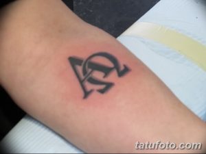 Фото татуировки с изображением греческих букв Альфа и Омега на предплечье. Черный контурный рисунок, минималистичный дизайн, четкие линии.
