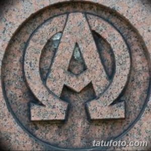 Фотография татуировки, изображающей символы Альфа и Омега, заключенные в круг с текстурой камня.