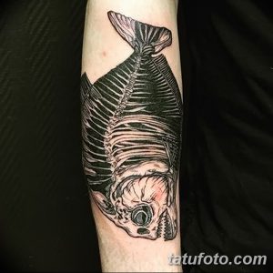 Фото тату скелета рыбы, выполненного в технике blackwork с четкими линиями и детальной проработкой, на руке. Стильный рисунок татуировки.