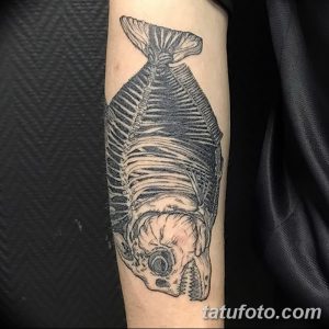 Фото тату скелета рыбы, выполненного в технике blackwork, на руке. Простой и стильный рисунок татуировки.