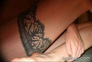 Фото тату: татуировка на бедре, имитирующая кружевной пояс. Черно-белый рисунок татуировки с детализированным узором кружева.