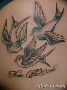 Фото тату: три ласточки в стиле олд скул с надписью "Three Little Birds". Яркие цвета, четкие контуры, классический дизайн.