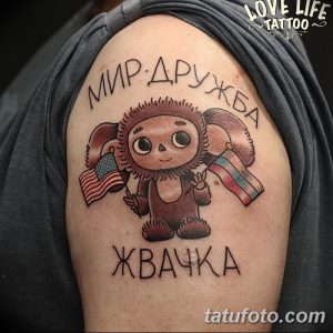 Фото татуировки на плече с изображением Мишки, держащего флаги США и СССР, с надписями 'МИР ДРУЖБА' и 'ХВАЧКА'.