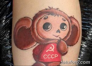 Фото татуировки на руке с изображением Мишки, символа Олимпиады-80, в красной майке с серпом и молотом и надписью 'СССР'.