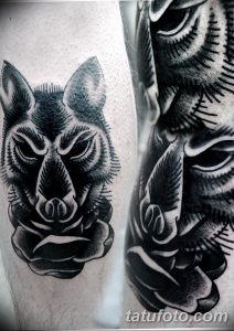 Фото тату головы волка в технике blackwork на предплечье. Черно-серая татуировка с использованием плотных заливок и геометрических узоров.