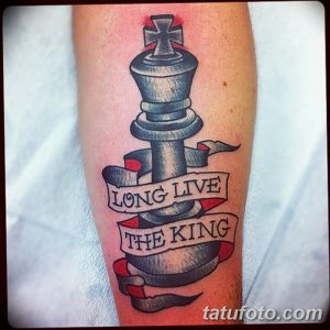 Фото тату на руке с изображением шахматного короля и ленты с надписью "LONG LIVE THE KING". Стильный рисунок в традиционном стиле.