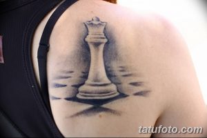 Серо-белая татуировка на плече с изображением шахматного короля. Реалистичный рисунок с детальной проработкой фигуры и мягкими тенями.