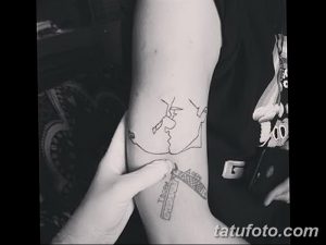 Фото минималистичной татуировки на руке, изображающей портрет Чарли Чаплина. Тонкие линии и лаконичный дизайн рисунка татуировки.