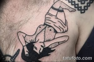 Фото тату на груди мужчины, изображающее девушку в пикантной позе в стиле олд скул. Яркий рисунок татуировки с четкими контурами.
