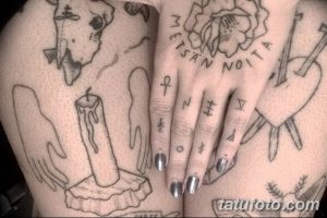 Фото тату на теле, изображающее череп, горящую свечу, руку и различные символы в черном цвете. Детализированный рисунок татуировки.