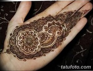 Фото тату мехенди на руке, выполненное в традиционном стиле с использованием коричневых оттенков. Детализированный цветочный орнамент украшает ладонь.