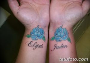 Фото тату: парные татуировки с голубыми розами и именами 'Elijah' и 'Jaden' на запястьях, выполненные в ярком цвете.