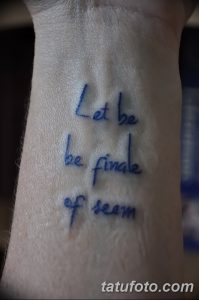Фото тату: минималистичная надпись 'Let be be finale of seam' на запястье, выполненная тонкими линиями черными чернилами.