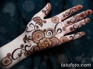 Фото тату мехенди на руке, выполненное в ярких коричневых тонах с использованием цветочных мотивов и геометрических узоров.