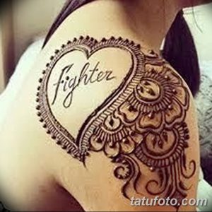 Фото тату мехенди на плече с надписью 'Fighter' внутри сердца, окруженного восточным орнаментом. Символ силы и борьбы.