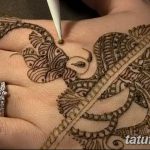 Фото тату хной на руке, изображающего слона, восточный стиль, детальная проработка, коричневые оттенки, мастер наносит узор.