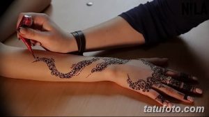 Фото процесса нанесения тату хной на руку, мастер наносит узор с помощью специального инструмента, детальная проработка, восточный стиль, коричневые оттенки.