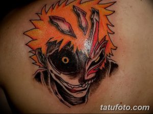 Фото тату на плече с изображением маски Холлоу из аниме Bleach, выполненное в ярких оранжевых и черных тонах.