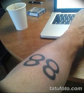 Фото минималистичной татуировки на запястье с изображением цифры 88, выполненной черными чернилами. Простой и лаконичный дизайн.