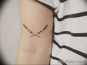 Фото тату: две тонкие веточки, перекрещенные на предплечье. Минималистичный стиль, черные линии, простой дизайн.