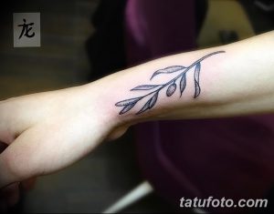 Фото тату: тонкая веточка оливы на запястье. Черно-белый рисунок, минималистичный стиль, изящное исполнение.