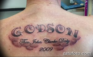 Фото тату надписи 'Godson' выполненной черными чернилами на спине мужчины, с добавлением облаков и указанием года 2009.